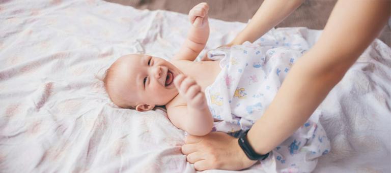 A happy baby on a blanket looking up at their parent