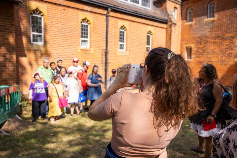 A woman taking a photo of a group of adults and children