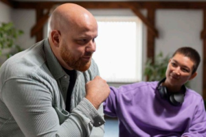 Photo of a person placing a comforting hand on a man's shoulder