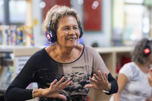 An older woman wearing headphones and doing exercise