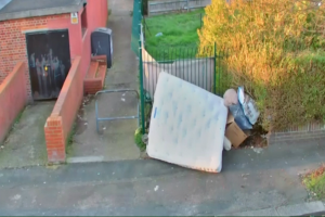 Fly-tipped rubbish including a mattress, next to a footpath