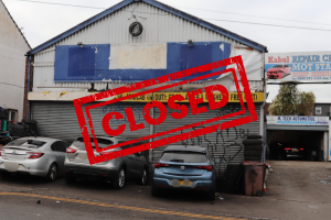 Garage with abandoned cars. Photo has an overlay of a 'CLOSED' stamp in red