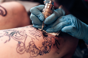 Close-up photo of a tattoo artist wearing sterile gloves while tattooing a design on a person