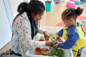 Adult and child exploring natural materials during a play session
