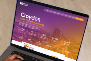Laptop displaying the Invest in Croydon website homepage with borough statistics and skyline imagery
