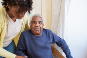 An older person being assisted into a chair by a younger person
