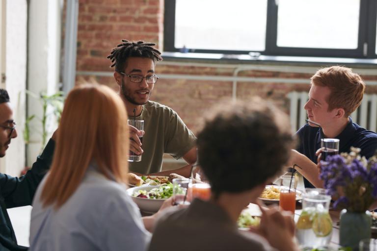 A group of friends sitting around a table eating and drinking.