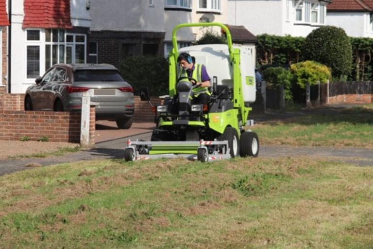 Council worker mowing a grass verge on a ride on lawn mower