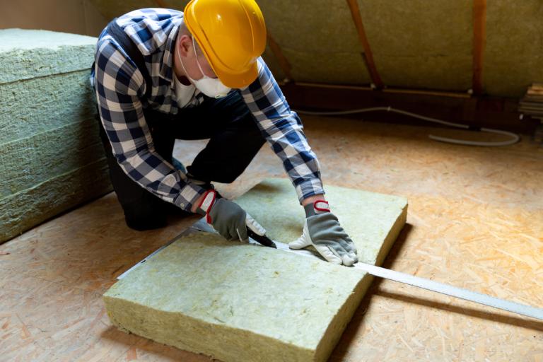 A person wearing protective clothing, installing thermal roof insulation