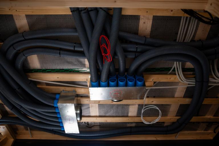 Energy efficient ventilation ducts and wiring within wooden beams of a house under construction.